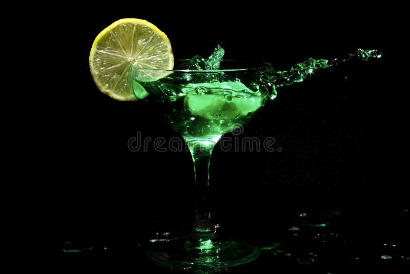 Green cocktail splashing in a glass