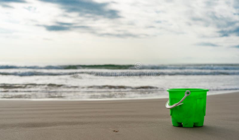 Green bucket on the beach sand