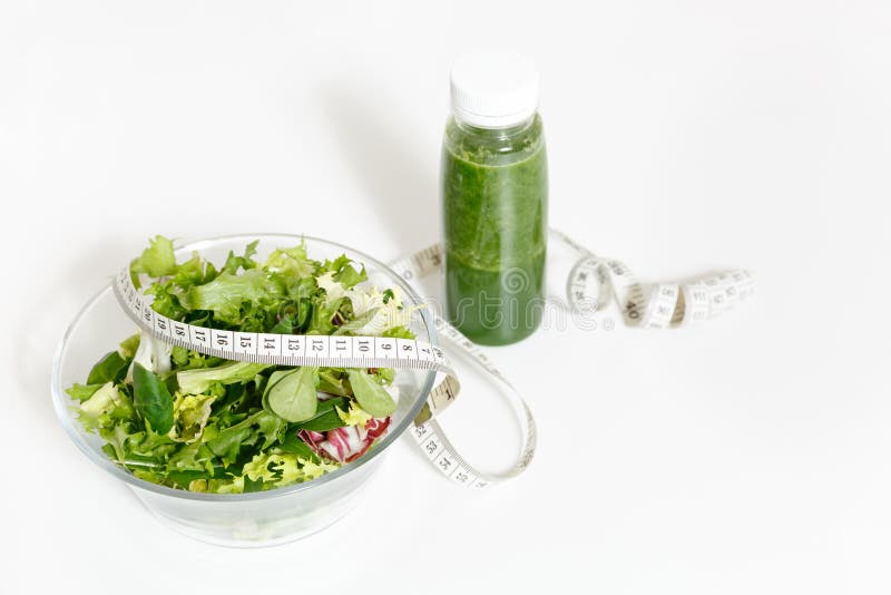 Green detox smoothies, vegetables salad in glass bowl, tailor measuring tape isolated on white background. Proper stock image Green detox smoothies, vegetables salad in glass bowl, tailor measuring tape isolated on white background. Proper stock image