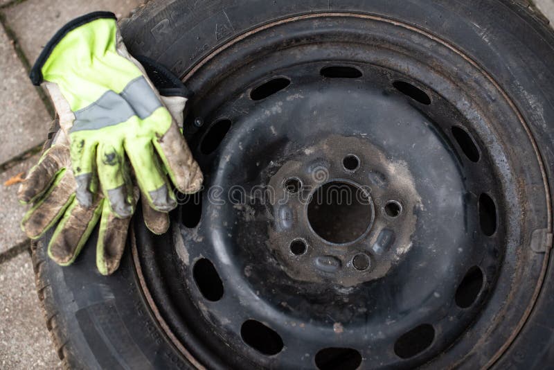 Green dirty gloves are placed on a used car wheel royalty free stock photo