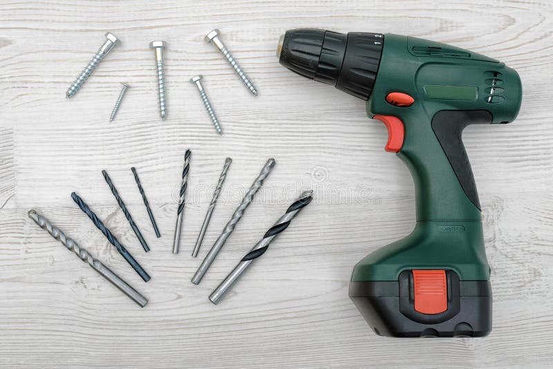A Green Electric Drill, Several Twisted Drill Bits and Bolts Placed on