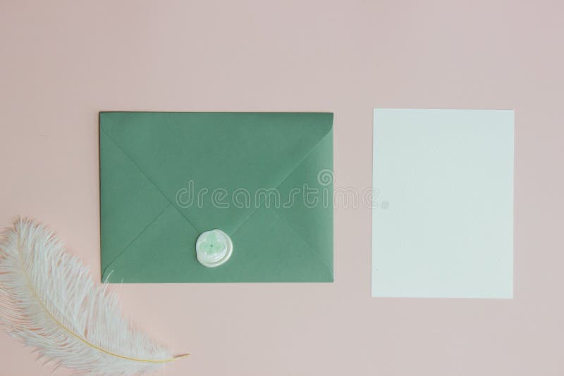 Green envelope with white letter and feather over the pink background. royalty free stock photography
