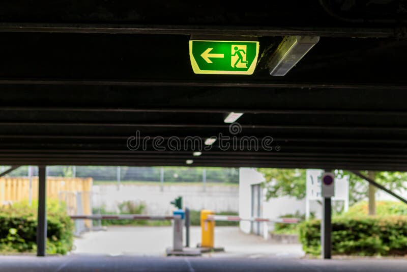 Green exit sign with running person and green arrow shows guidance system signage in a parking lot for rescue evacuation safety stock photo