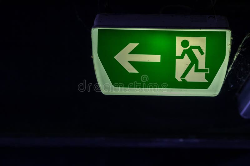 Green exit sign with running person and green arrow shows guidance system signage in a parking lot for rescue evacuation safety stock image