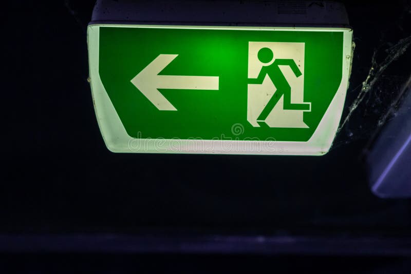 Green exit sign with running person and green arrow shows guidance system signage in a parking lot for rescue evacuation safety stock photos