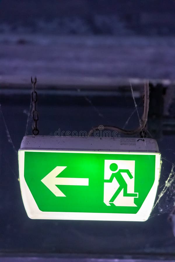 Green exit sign with running person and green arrow shows guidance system signage in a parking lot for rescue evacuation safety stock photo