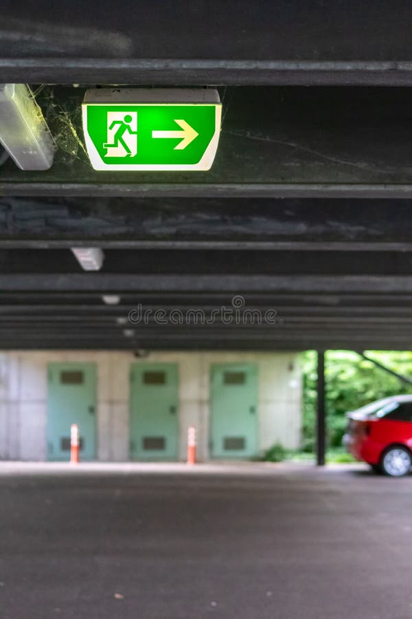 Green exit sign with running person and green arrow shows guidance system signage in a parking lot for rescue evacuation safety royalty free stock photos
