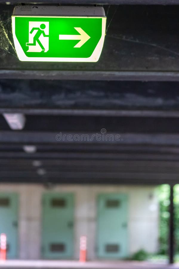 Green exit sign with running person and green arrow shows guidance system signage in a parking lot for rescue evacuation safety royalty free stock photography