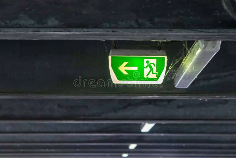 Green exit sign with running person and green arrow shows guidance system signage in a parking lot for rescue evacuation safety royalty free stock image