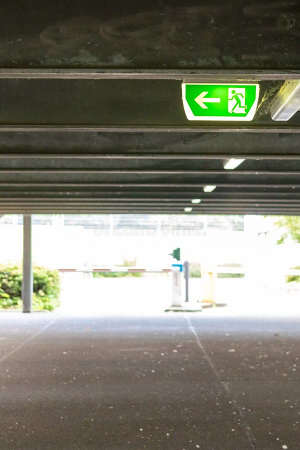 Green exit sign with running person and green arrow shows guidance system signage in a parking lot for rescue evacuation safety stock image