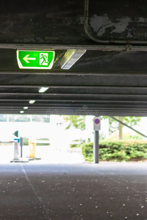 Green exit sign with running person and green arrow shows guidance system signage in a parking lot for rescue evacuation safety stock photos