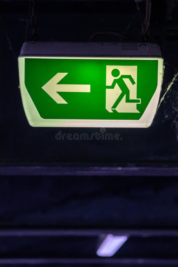 Green exit sign with running person and green arrow shows guidance system signage in a parking lot for rescue evacuation safety royalty free stock photography