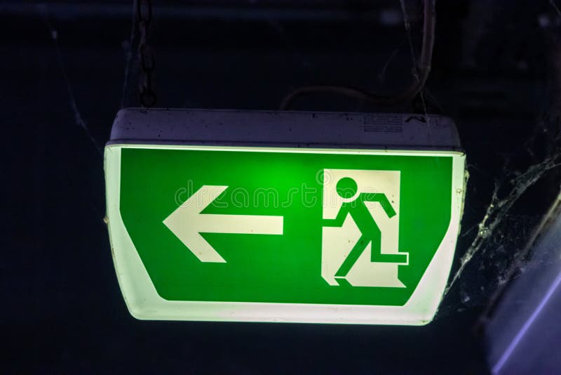 Green exit sign with running person and green arrow shows guidance system signage in a parking lot for rescue evacuation safety royalty free stock photography