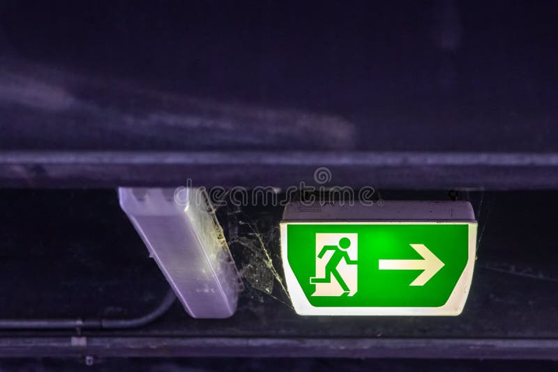 Green exit sign with running person and green arrow shows guidance system signage in a parking lot for rescue evacuation safety stock images