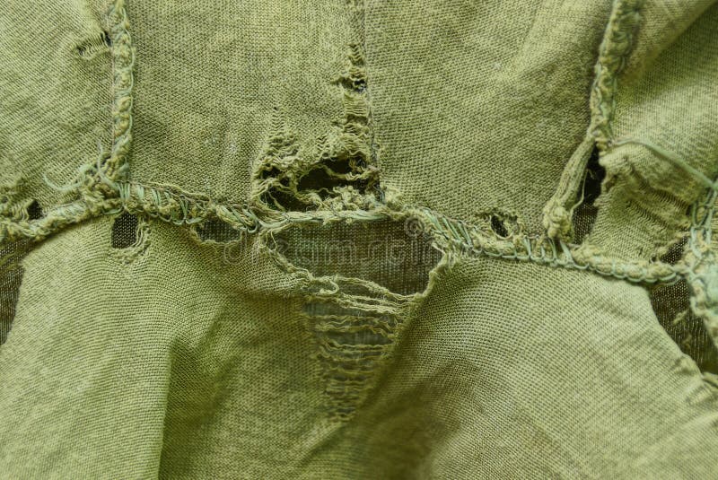 Green fabric texture of torn clothes. With a hole stock photo