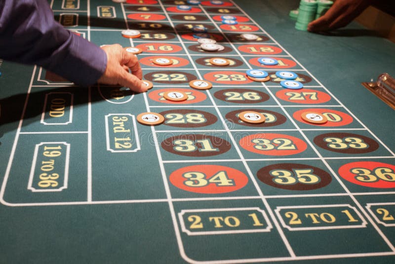 Green felt roulette table with players placing bets
