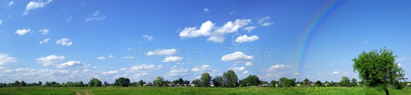 Green field panorama with rainbow