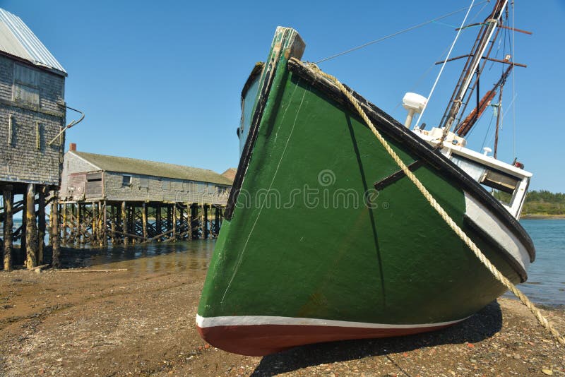 Green Fishing boat laying on side low tide stock image