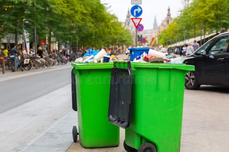 Green garbage can on sidewalk, european city stock image