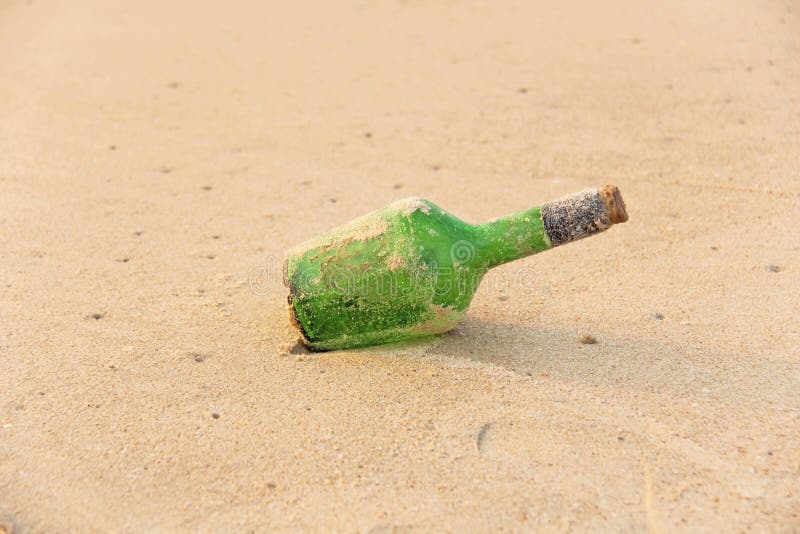 Green Glass Bottle with a Message Inside on the Seashore on the Beach