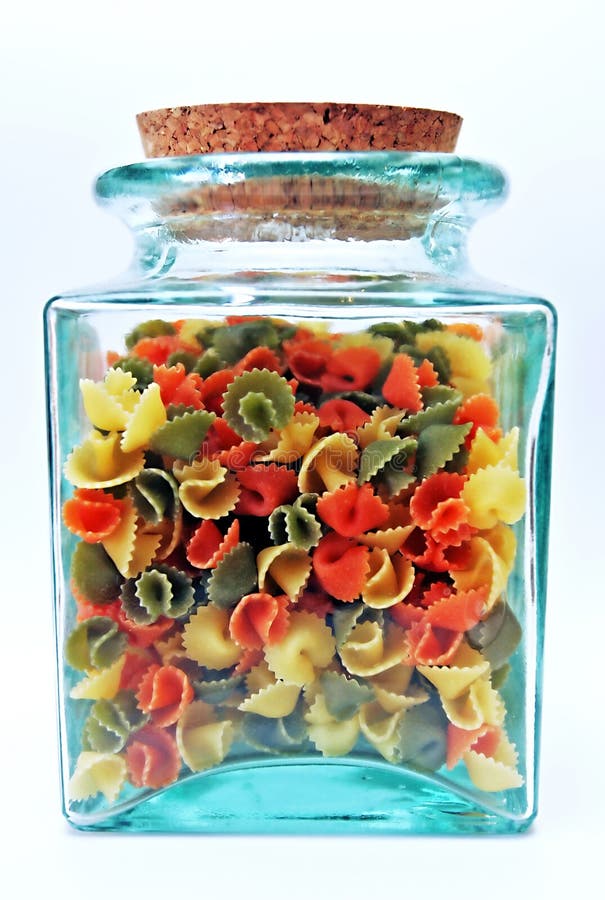 Green, glass, see through jar with cork lid containing colorful pasta shells.
