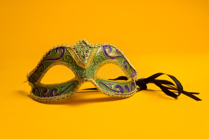 Green, gold, purple mardi gras mask on a bright yellow background. Green, gold, purple mardi gras mask on a bright yellow background