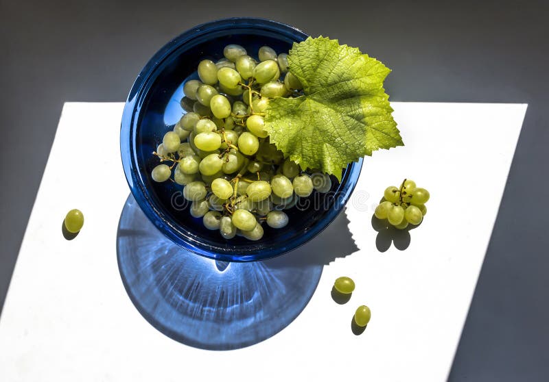 Green Grapes in a Blue Glass Vase in the Sun View from Above Stock