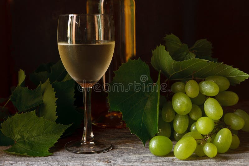 Green grapes with leaves, glass, bottle of white wine on vintage