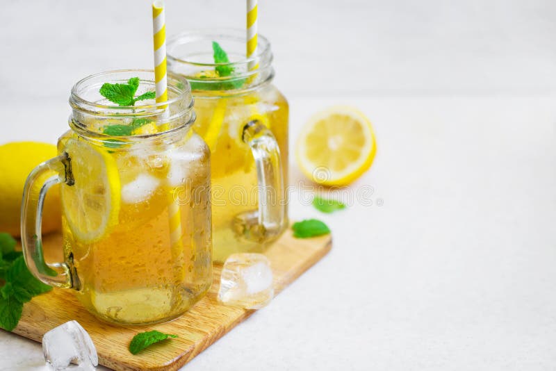 Green ice tea with lemon and mint in a glass jar.