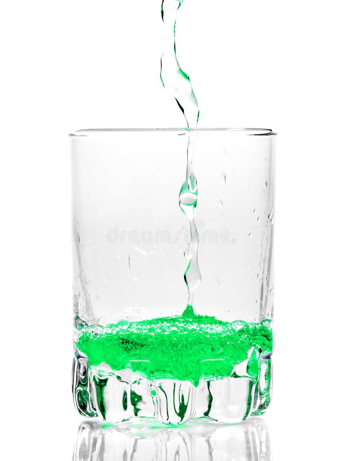 Green liquid being poured into a transparent glass