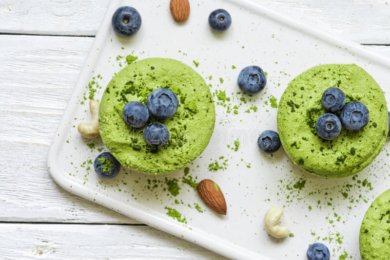 Green matcha vegan raw cakes with blueberries, mint and nuts. healthy delicious food. Top view stock photos
