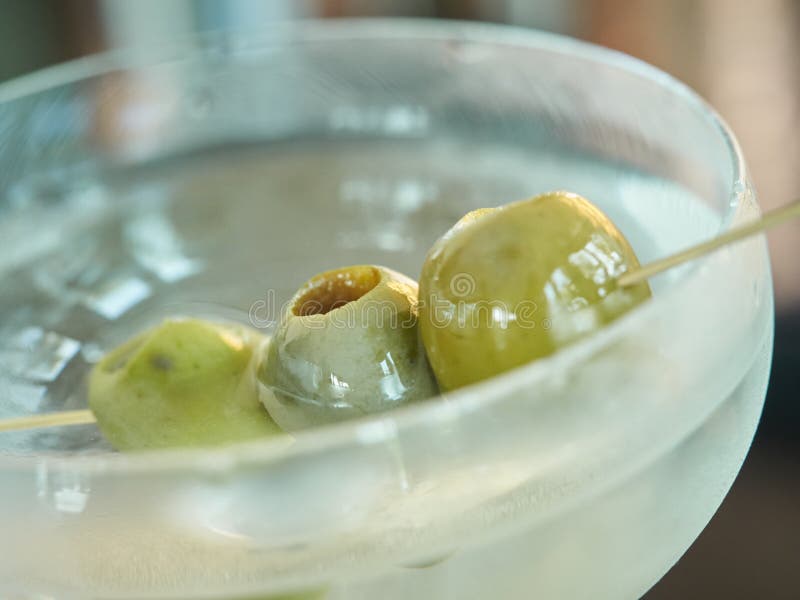 Green olives on a stick in a martini glass shallow depth of field