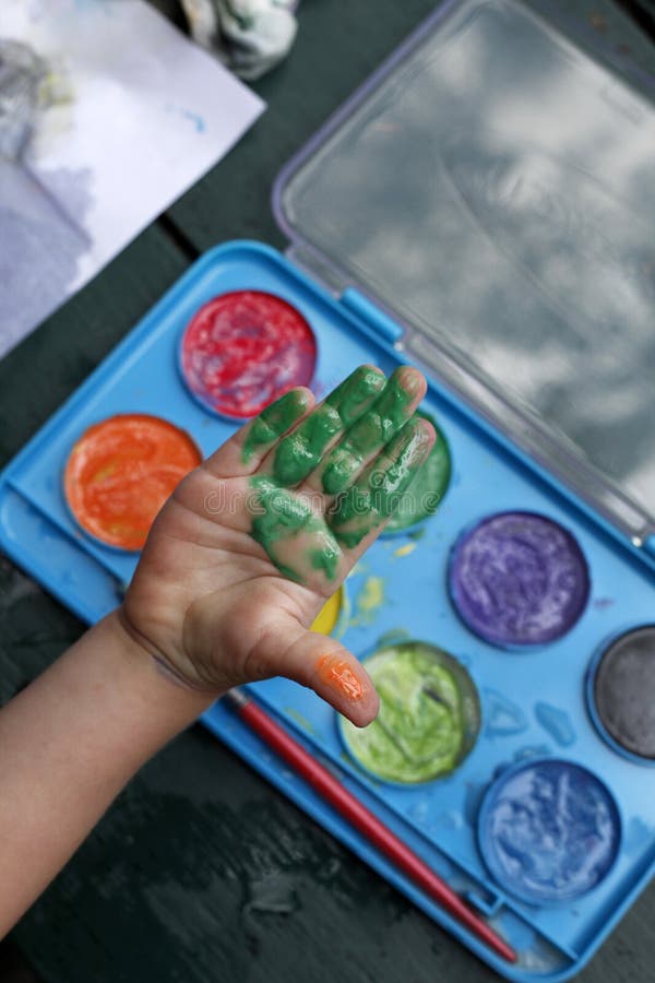 Ninos pequenos mano cubierto en verde pintar mientras la pintura Agua colores.