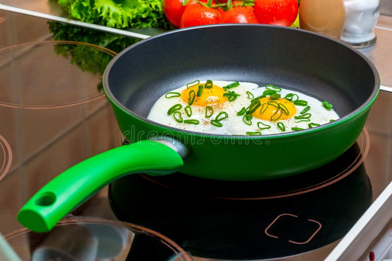 Green Pan with Scrambled Eggs from Two Eggs on a Glassceramic Stove