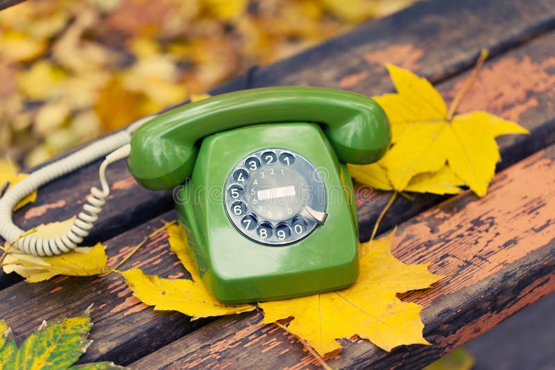 Green phone on bench in autumn park