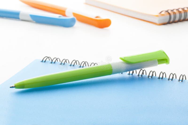 Green plastic ball pen with blue notebook