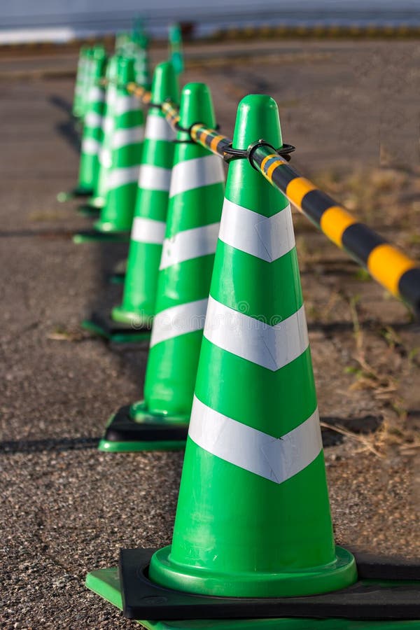 Green Safety Cones with White Stripes Placed in a Row, Selective Focus