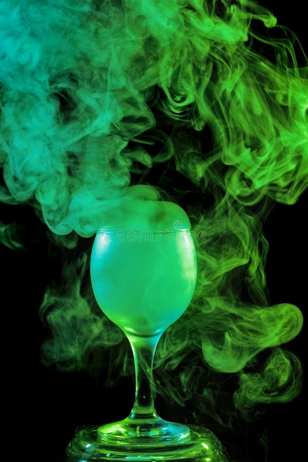 Abstract art. Hookah green smoke in cocktail glass on a white background. Witch potion background for Halloween. Unusual bar drink. Drink in the glass with the effect of dry ice. Abstract art. Hookah green smoke in cocktail glass on a white background. Witch potion background for Halloween. Unusual bar drink. Drink in the glass with the effect of dry ice.