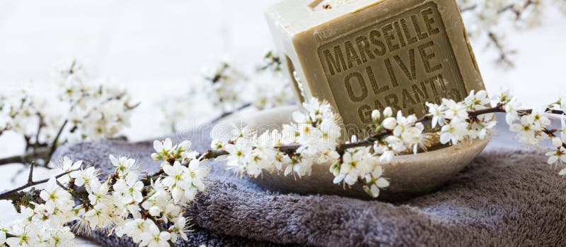 Green soap with olive oil over towel and fresh flowers