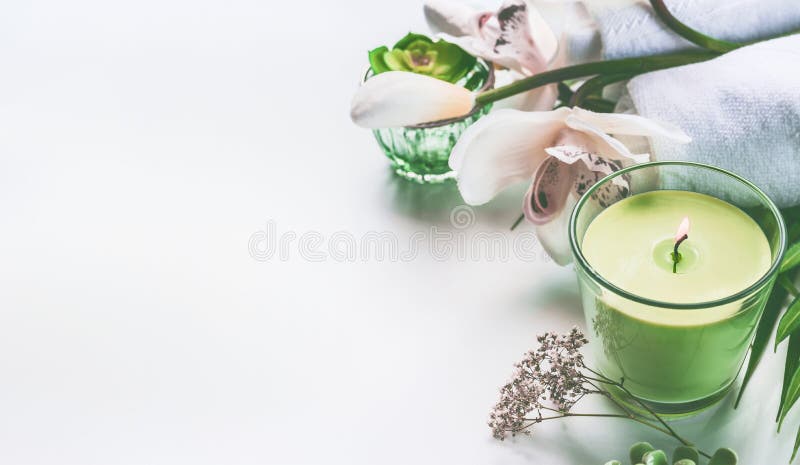 Green spa or wellness background with towels, candle, orchid flowers and accessories stock photo