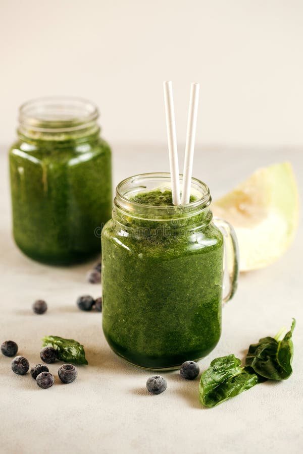 Green Spinach Blueberry and Melon Smoothie in Mason Jar on White