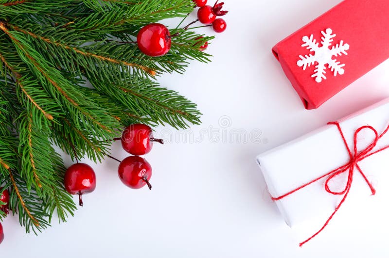 Green spruce branches decorated with berries and gift boxes on a white background. New Years, Christmas decor. Festive theme.