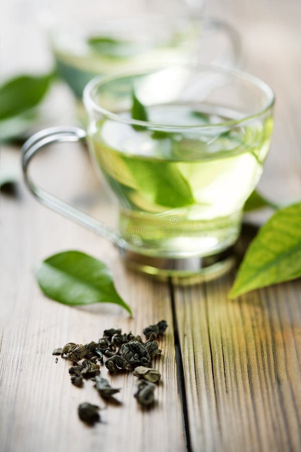 Primo piano del secco di tè verde, e una tazza con tè verde fresco.