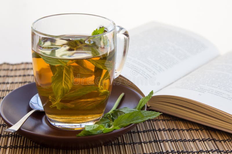 Green tea and leaves of mint in a glass cup with a book