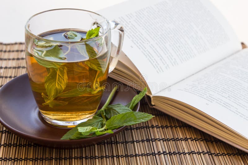 Green tea and leaves of mint in a glass cup with a book