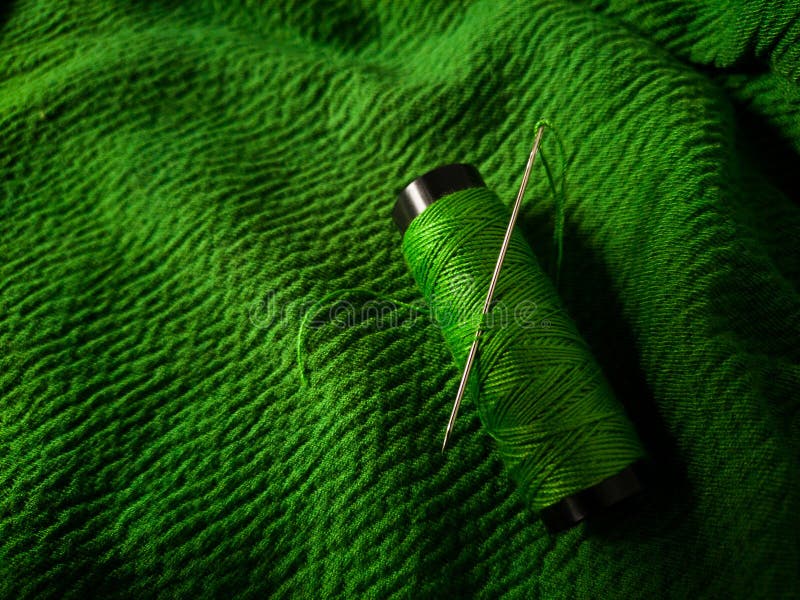 Green thread spool lies on a green textured fabric royalty free stock photos