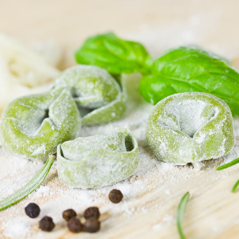 Raw Tortellini With Green Spinach Leaves On Wooden Background With