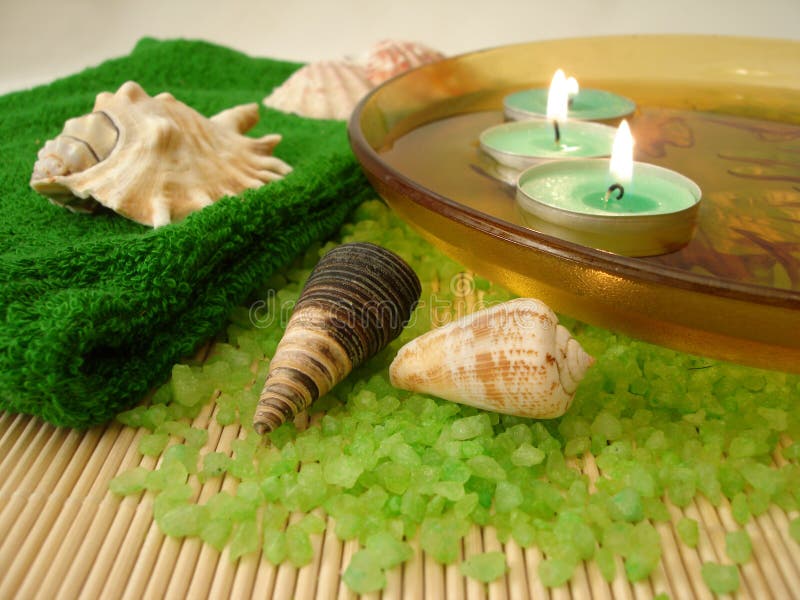 Green towel, shells, candles in plate with water and salt on a s