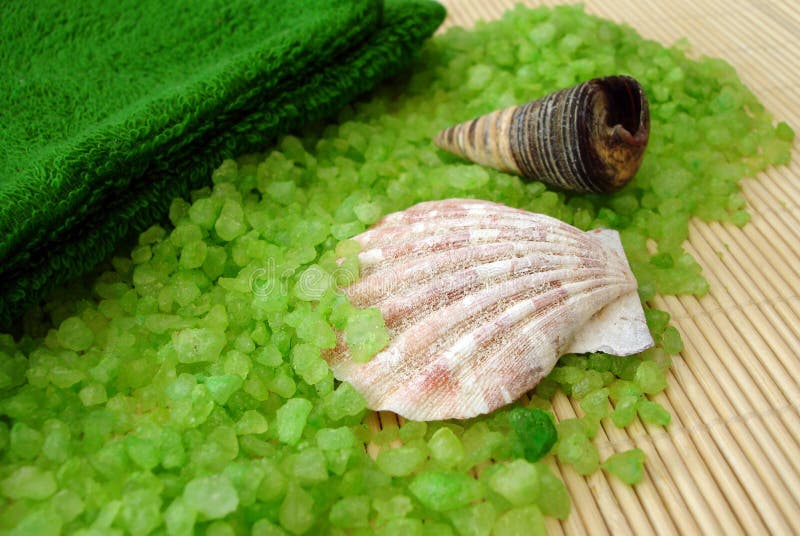 Green towel, shells and salt on a straw mat