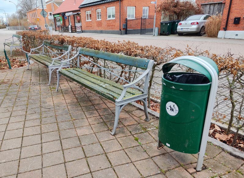Green trash bin and benches in urban setting stock photo